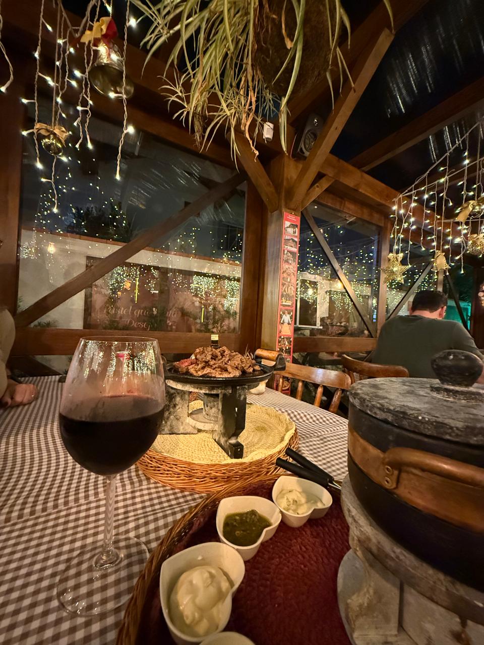 Mesa com taça de vinho no ambiente aconchegante da Pastelaria Blumenau, em Piçarras